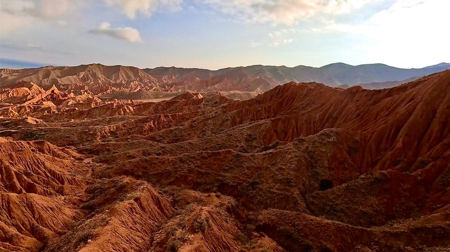 The eroded red badlands of Fairy Tale Canyon at low sun, ridges and gullies running towards distant hills.